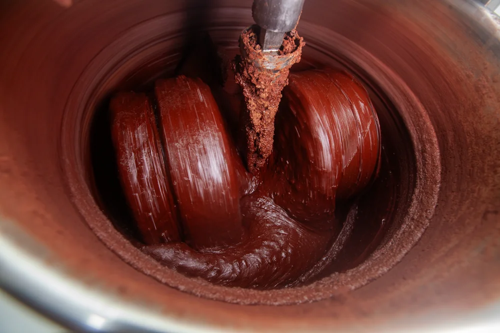 Cokelat cair yang sudah halus dan mengkilap berputar di dalam melangeur